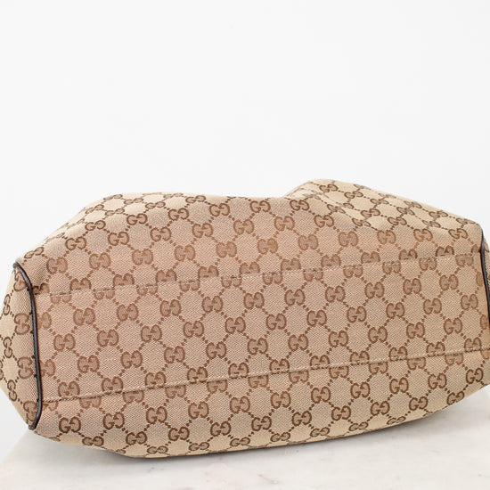 Bottom view of beige handbag with Gucci monogram pattern on a white background