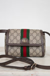 Gucci GG Supreme canvas shoulder bag with brown leather trim, a green and red web stripe, and a gold-tone GG logo on the front flap, shown with a adjustable brown strap on a light marble surface against a white background.