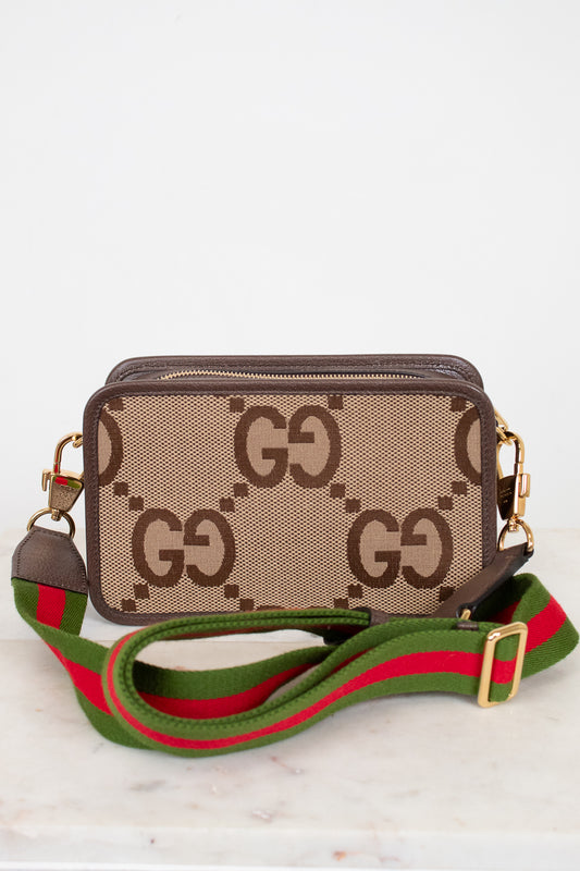 Designer handbag with a distinctive pattern and colorful strap on a light background
