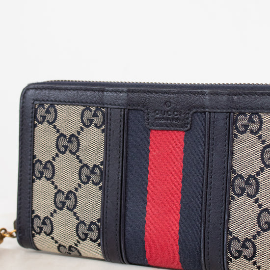 Navy and monogrammed zip around wallet with red and navy striped center detail against a plain background