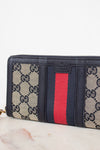 Navy and monogrammed zip around wallet with red and navy striped center detail against a plain background