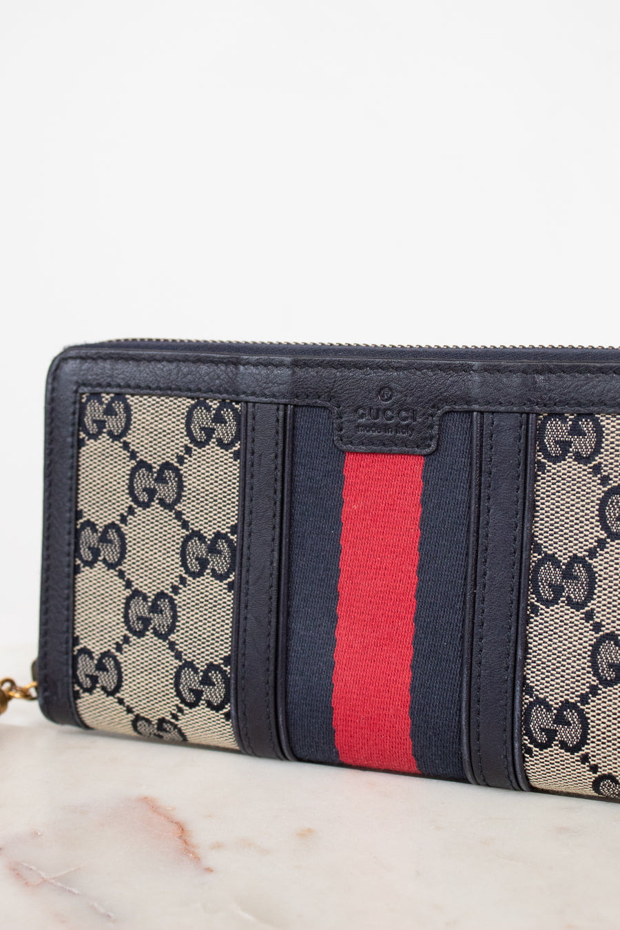 Navy and monogrammed zip around wallet with red and navy striped center detail against a plain background