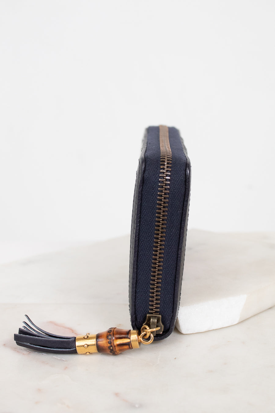 Close-up of side view of wallet showing zipper with gold and bamboo details
