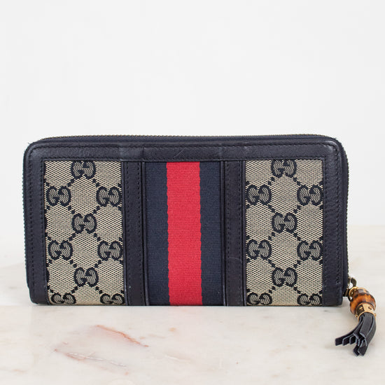 Back view of navy and monogrammed zip around wallet with red and navy striped center detail with gold and bamboo zipper 
