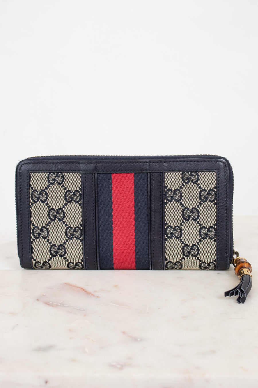 Back view of navy and monogrammed zip around wallet with red and navy striped center detail with gold and bamboo zipper 