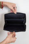 Hands holding open wallet showing many card slots, inserts, and interior zipper detail