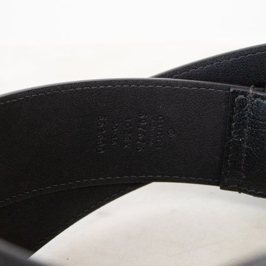 Close-up of a black leather belt with visible stitching on a white background