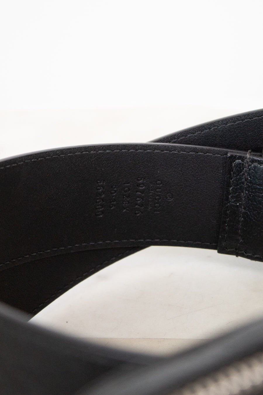Close-up of a black leather belt with visible stitching on a white background