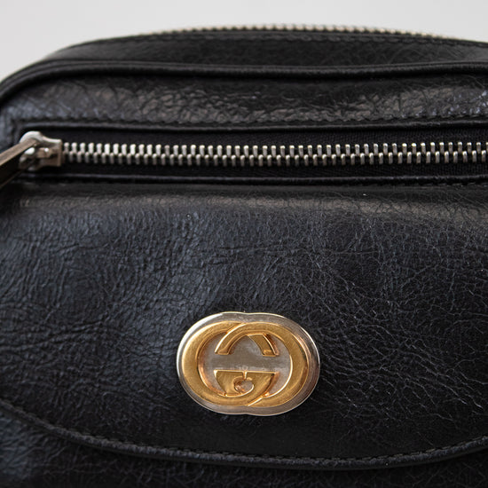 Black leather bag with a gold logo on a light gray background