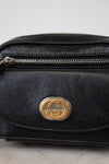 Black leather bag with a gold logo on a light gray background