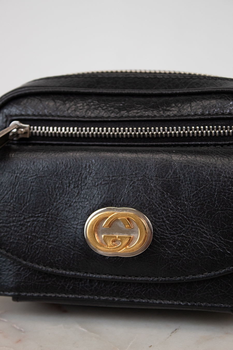 Black leather bag with a gold logo on a light gray background