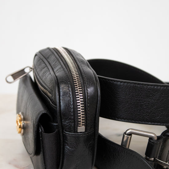 Black leather belt bag on a light marble surface