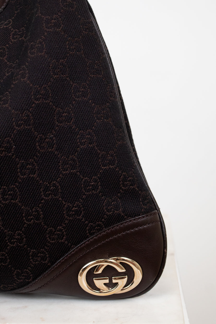 Gucci logo on brown purse with white background 