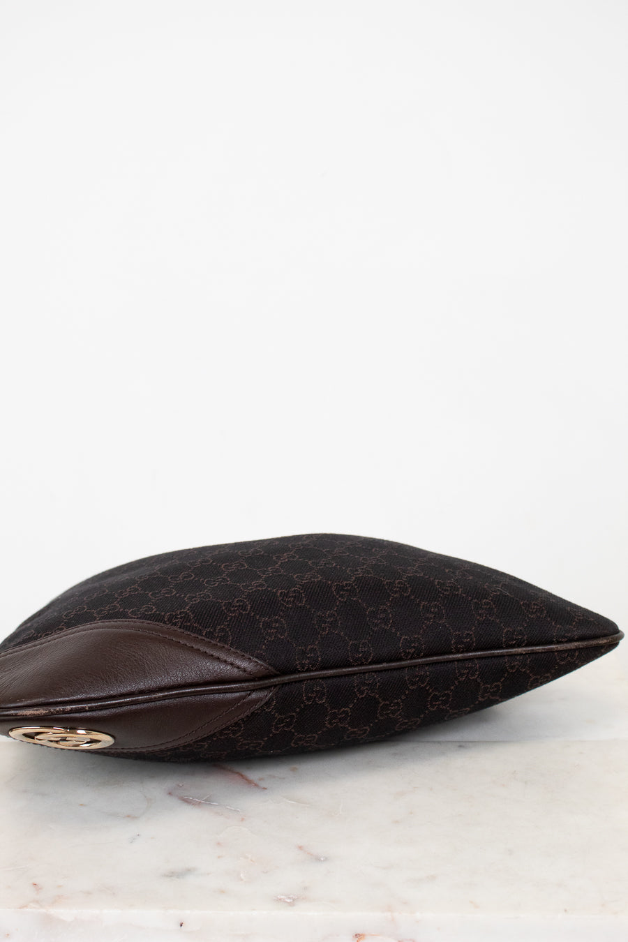 Bottom of brown Gucci purse on a white background
