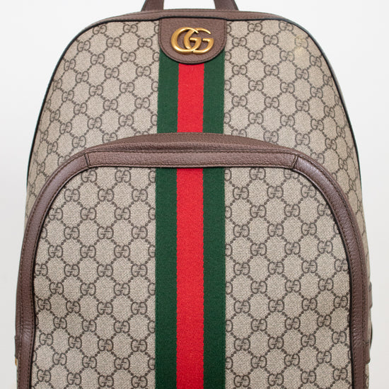 Gucci GG Supreme coated canvas backpack with brown leather trim, a green and red web stripe down the center, and a gold-tone GG logo on the front.