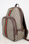 Gucci GG Supreme backpack in beige and brown monogram coated canvas with the signature green and red web stripe, brown leather trim, and gold-tone hardware, shown on a light background.