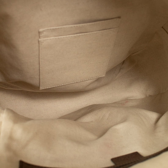 Close-up of the interior beige lining of a Gucci GG Supreme coated canvas backpack, showing a stitched interior pocket and a dark brown zipper track.