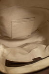 Close-up of the interior beige lining of a Gucci GG Supreme coated canvas backpack, showing a stitched interior pocket and a dark brown zipper track.
