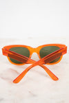 Orange translucent acetate sunglasses with dark lenses, resting on a light marble surface against a white background.
