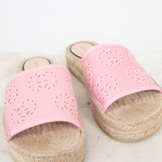 A pair of women's espadrille slide sandals with light pink cutout leather straps and natural jute-wrapped platform soles, displayed on a light marble surface against a white background.