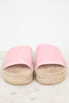 A pair of pink espadrille slide sandals with laser-cut circular patterns on the straps and braided jute platform soles, shown on a light marble surface against a white background.