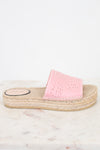 A single pink espadrille slide sandal with laser-cut circular patterns on the strap, resting on a light marble surface against a white background.