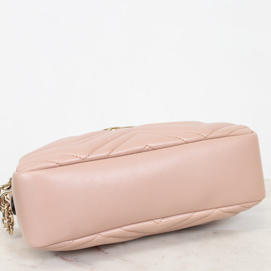 A light pink quilted leather shoulder bag shown from a side angle, resting on a white marble surface against a white background.