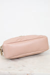 A light pink quilted leather shoulder bag shown from a side angle, resting on a white marble surface against a white background.