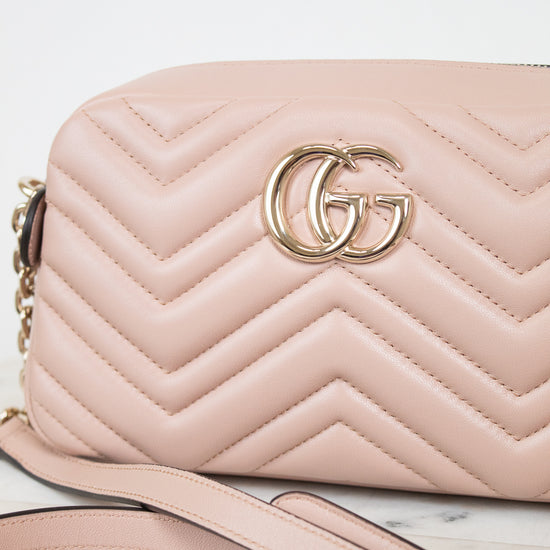 A light pink quilted leather shoulder bag with a gold-tone interlocking G logo on the front, resting on a white marble surface with a white background.