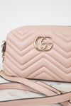 A light pink quilted leather shoulder bag with a gold-tone interlocking G logo on the front, resting on a white marble surface with a white background.