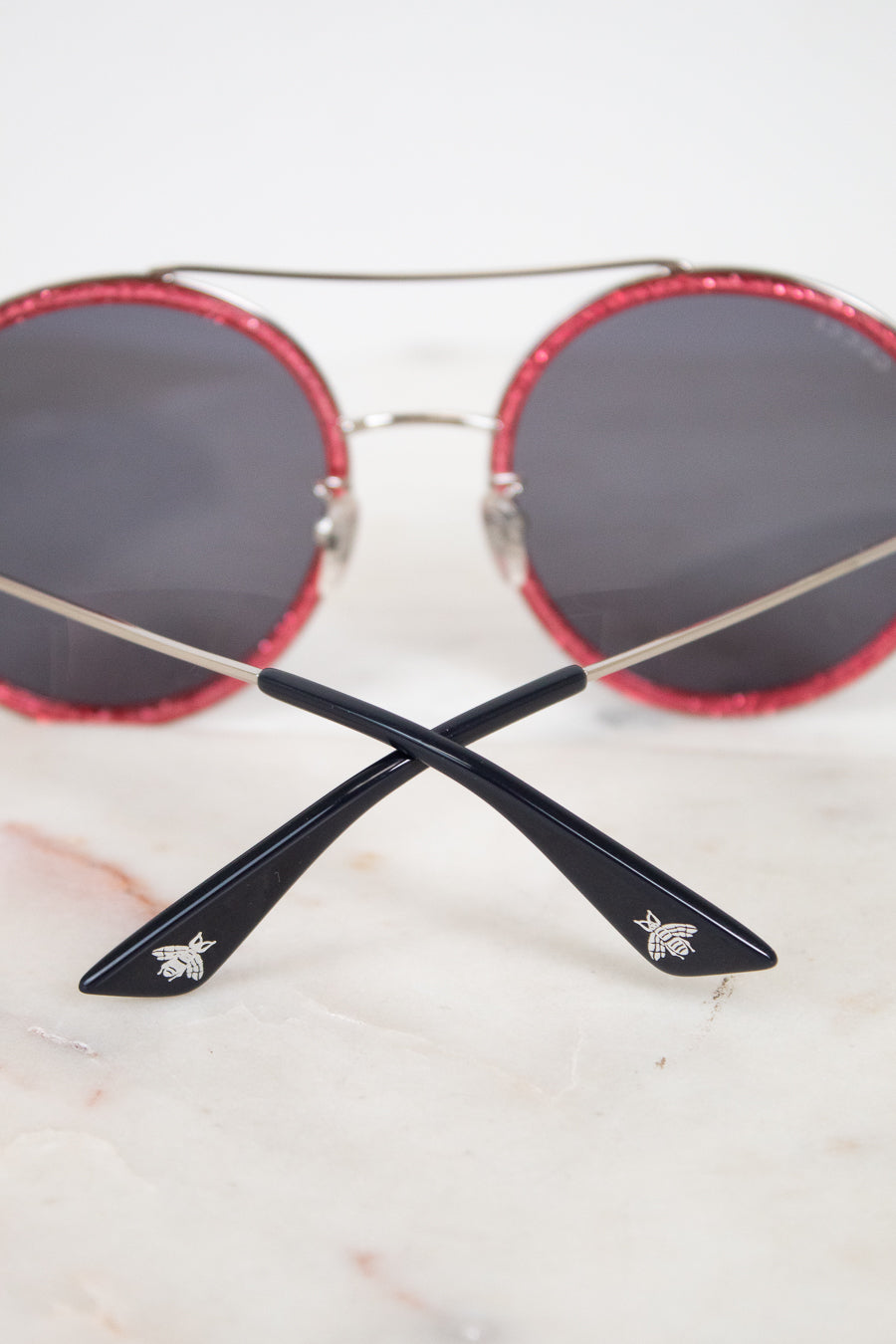 Round sunglasses with red frames and black lenses on a light background