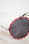 Sunglasses with red glitter frame and Gucci logo on a light background