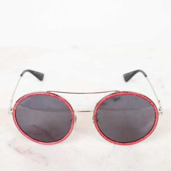 Round sunglasses with red frame and black lenses on a white background