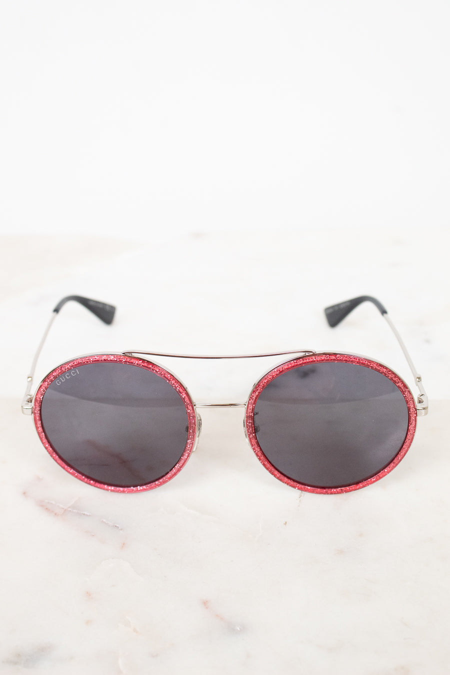 Round sunglasses with red frame and black lenses on a white background