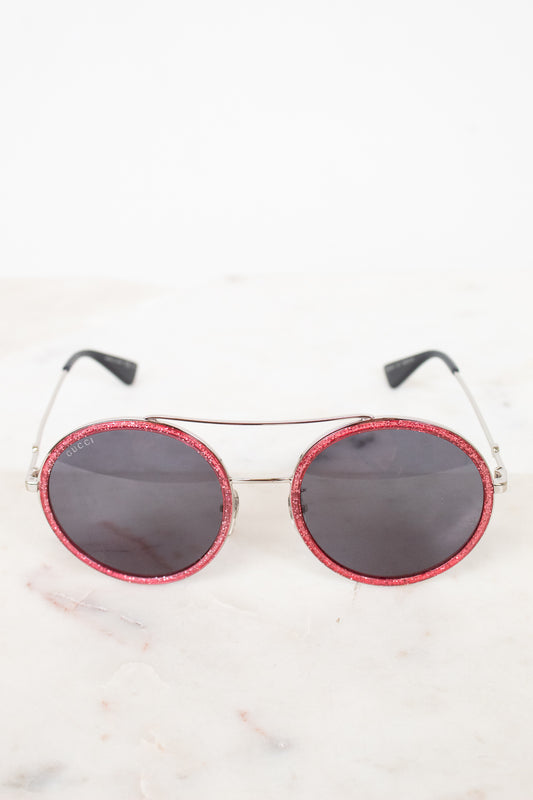 Round sunglasses with red frame and black lenses on a white background