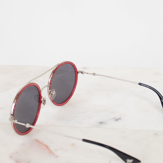 Sunglasses with red frames and black lenses on a marble surfaces