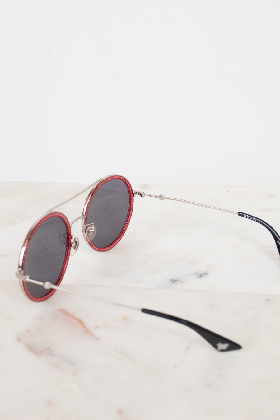 Sunglasses with red frames and black lenses on a marble surfaces