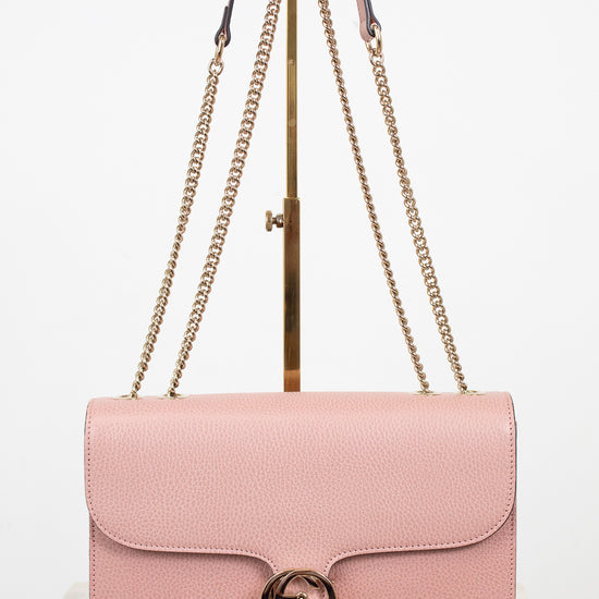 Pink handbag with gold chain strap on a white background