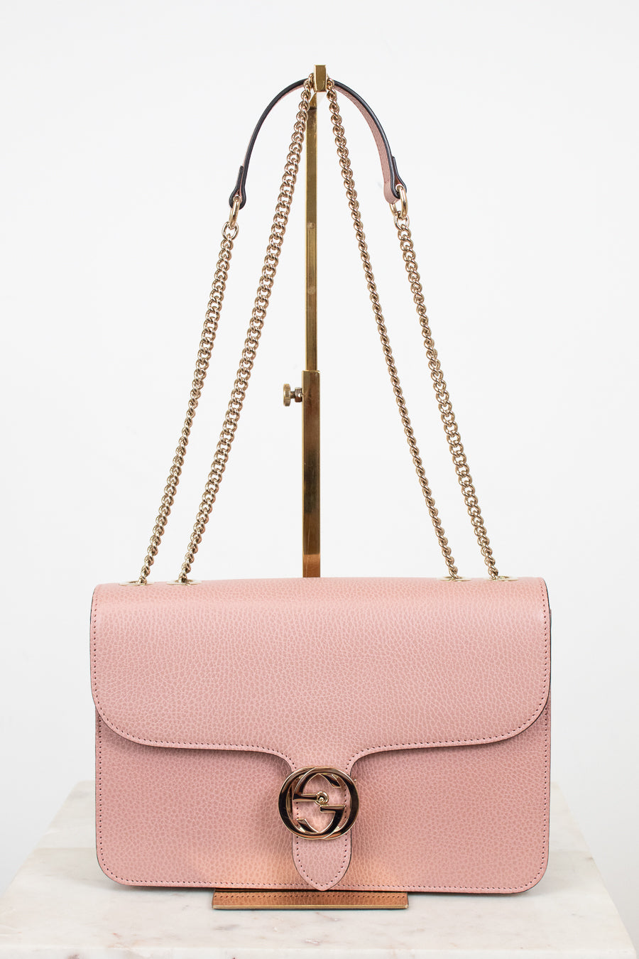 Pink handbag with gold chain strap on a white background