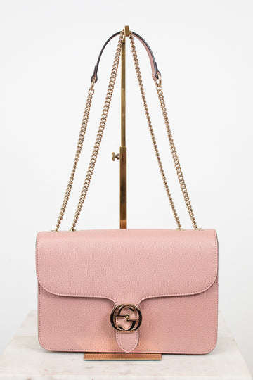 Pink handbag with gold chain strap on a white background