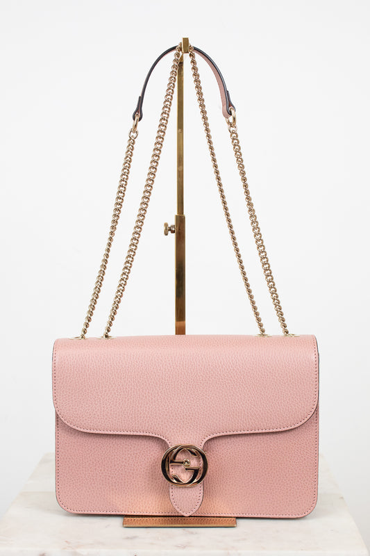 Pink handbag with gold chain strap on a white background
