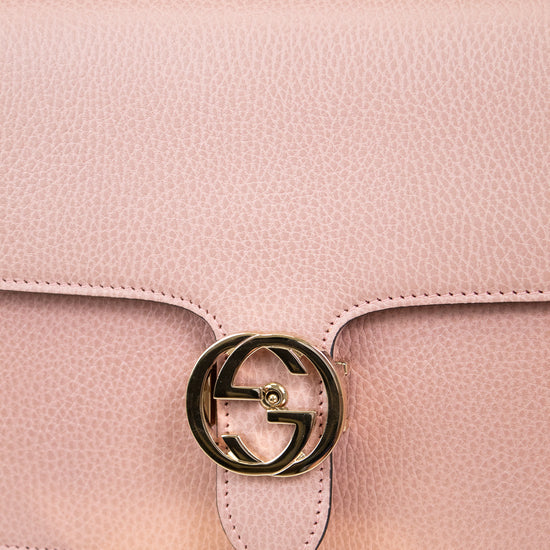 Pink handbag with a gold logo on a marble surface