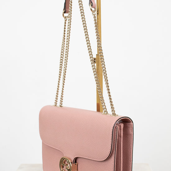 Pink handbag with gold chain strap on a white background