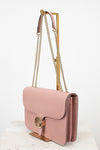 Pink handbag with gold chain strap on a white background