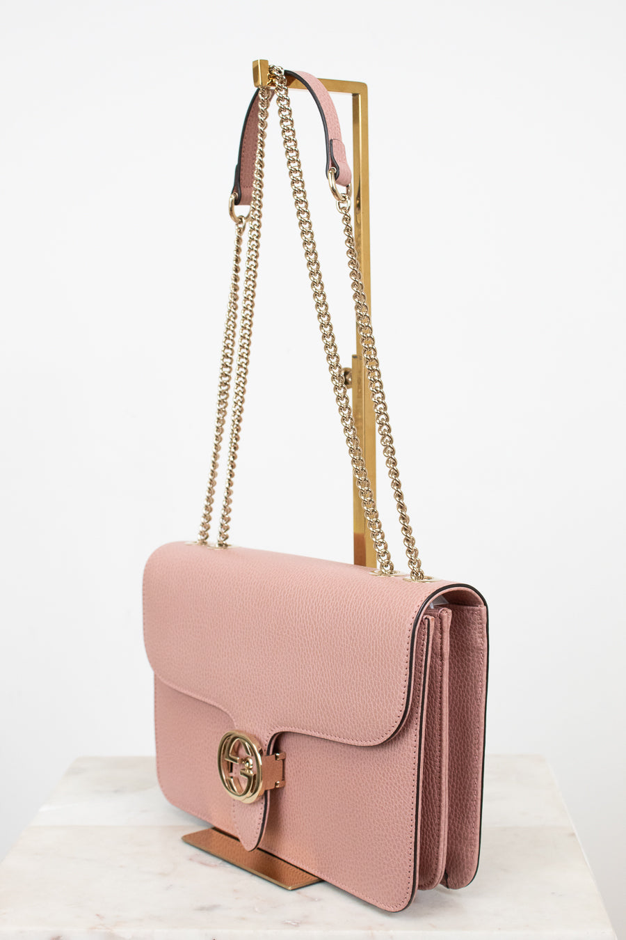 Pink handbag with gold chain strap on a white background