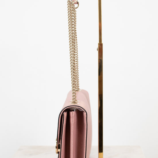 Side profile of pink handbag with a chain strap on a white background