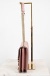 Side profile of pink handbag with a chain strap on a white background