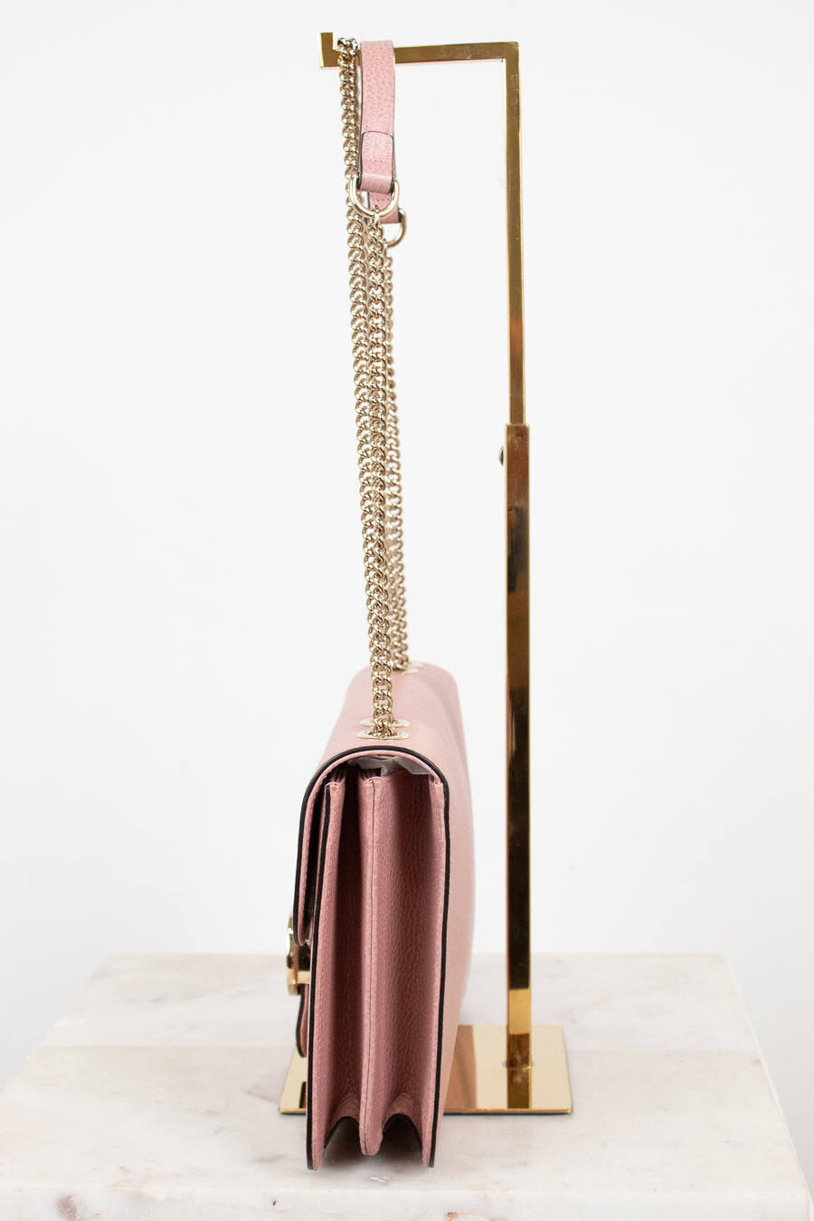Side profile of pink handbag with a chain strap on a white background