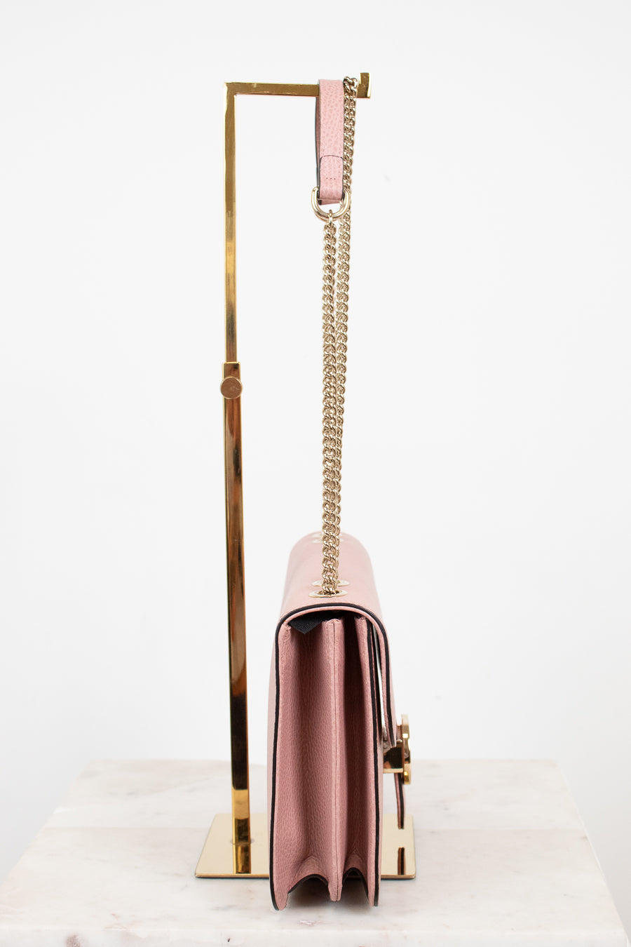 Side profile of pink handbag with a chain strap on a white background
