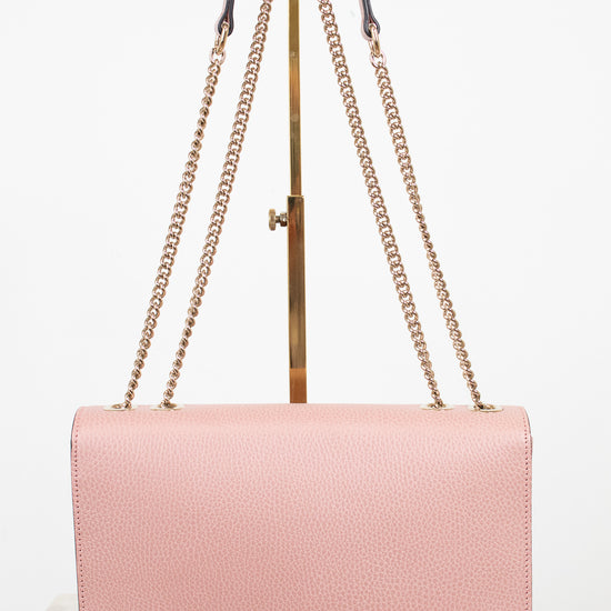 Pink handbag with gold chain strap on a white background